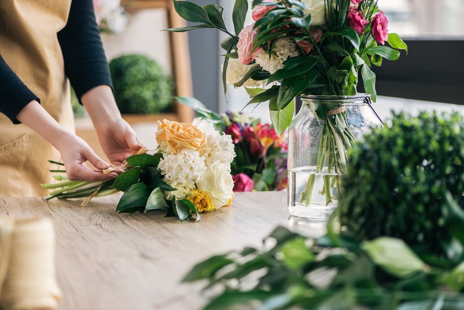 Florist arranging a vibrant flower bouquet on a wooden table
